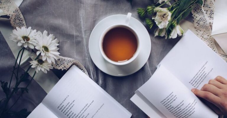 Poetry - White Ceramic Teacup With Saucer Near Two Books Above Gray Floral Textile