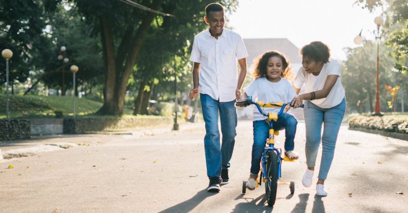 Teaching Strategies - Man Standing Beside His Wife Teaching Their Child How to Ride Bicycle